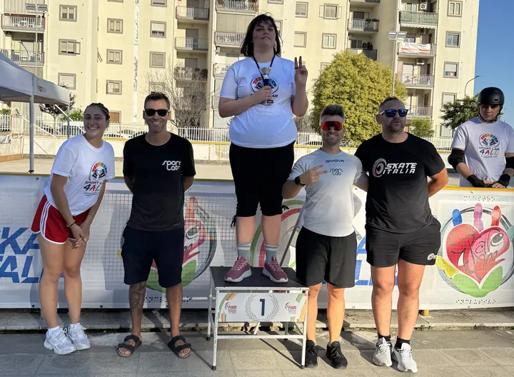 Atleta sul gradino più alto del podio della Coppa Italia Skate4All Zona Sud a Pontecagnano Faiano, con tecnici e accompagnatori