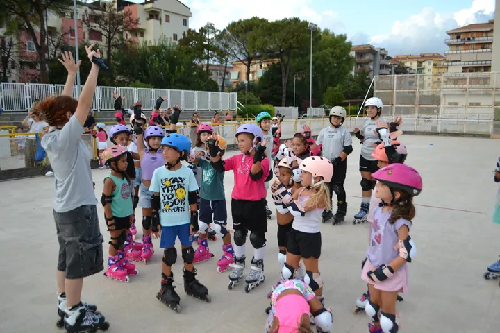 Bambini con caschi, protezioni e pattini a rotelle durante un corso di pattinaggio di ASD Sport Lab al pattinodromo di Pontecagnano, vicino Salerno