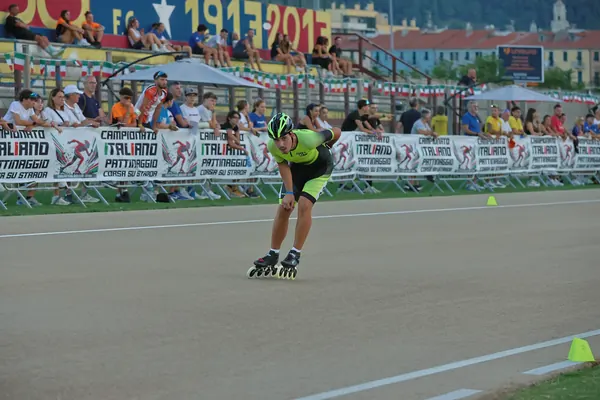 Giuseppe di ASD Sport Lab in maglia giallo fluo pattina davanti agli striscioni del Campionato Italiano Corsa su Strada