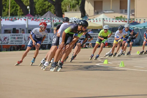 Pattinatori in curva davanti allo striscione del Campionato Italiano Pattinaggio Corsa su Strada