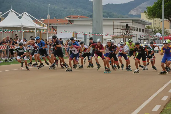 Il gruppo esce dalla curva davanti al pubblico a bordo pista
