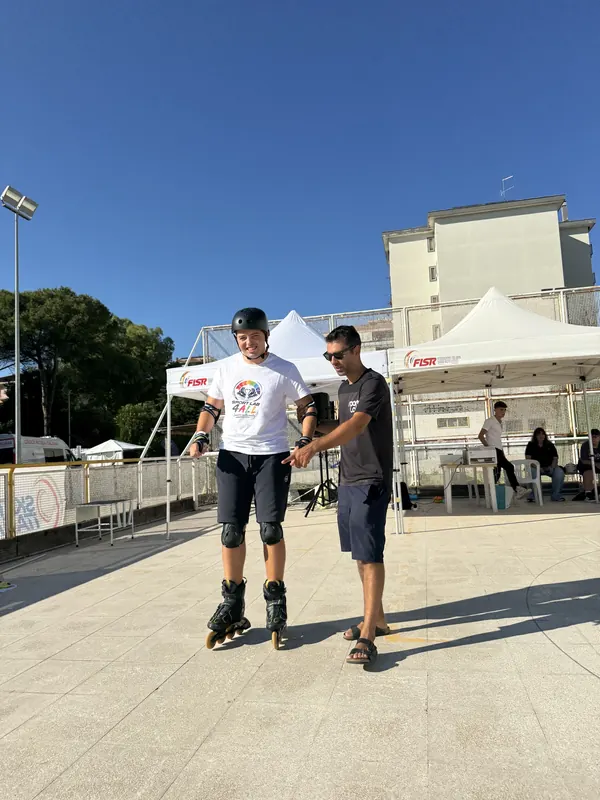 Atleta in pista accompagnato dal suo allenatore davanti ai gazebo della gara