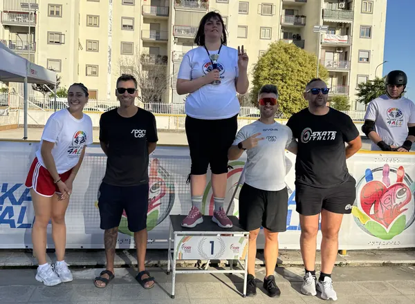 Atleta sul gradino più alto del podio con tecnici e accompagnatori
