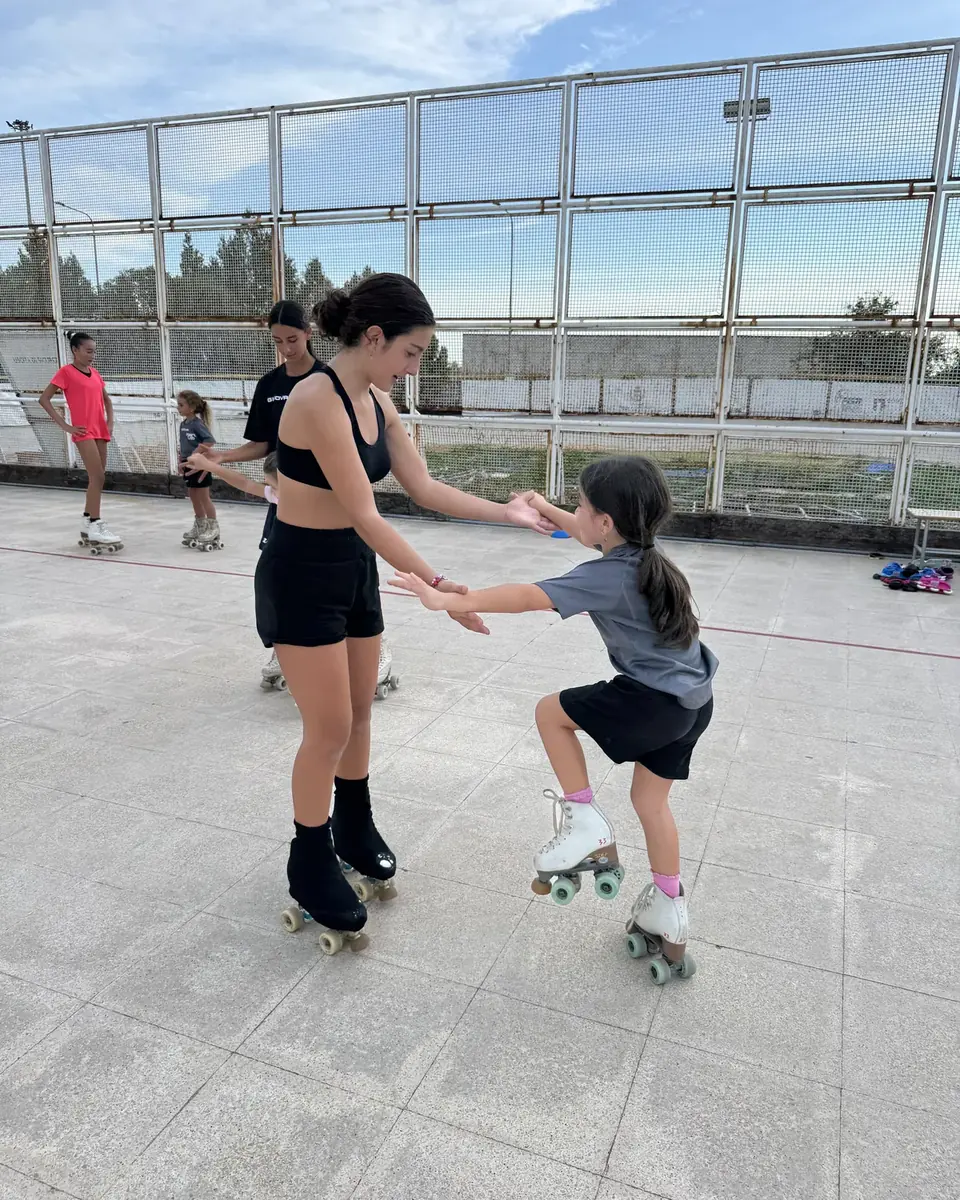 Istruttrice di ASD Sport Lab tiene per mano una bambina ai primi passi sui pattini a rotelle durante la lezione di pattinaggio artistico
