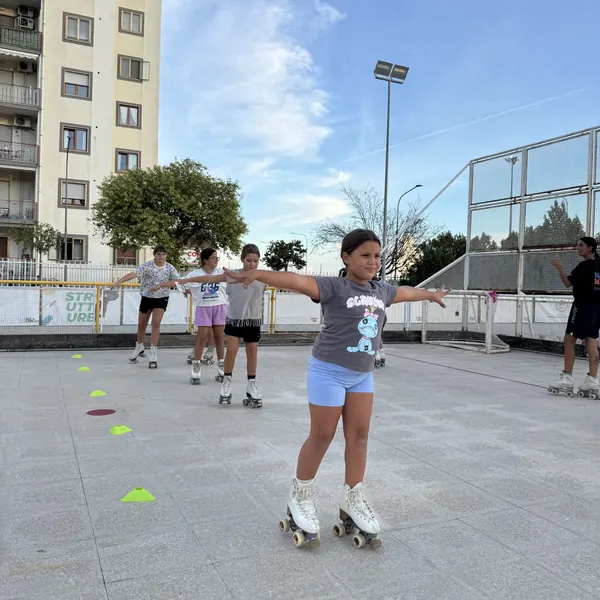 Bambina che pattina tra i coni con le braccia aperte durante il corso di pattinaggio artistico