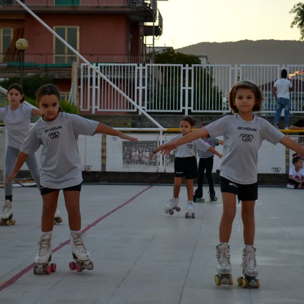 Bambine con le braccia aperte durante il corso di pattinaggio artistico sulla pista di Via Lazio al tramonto