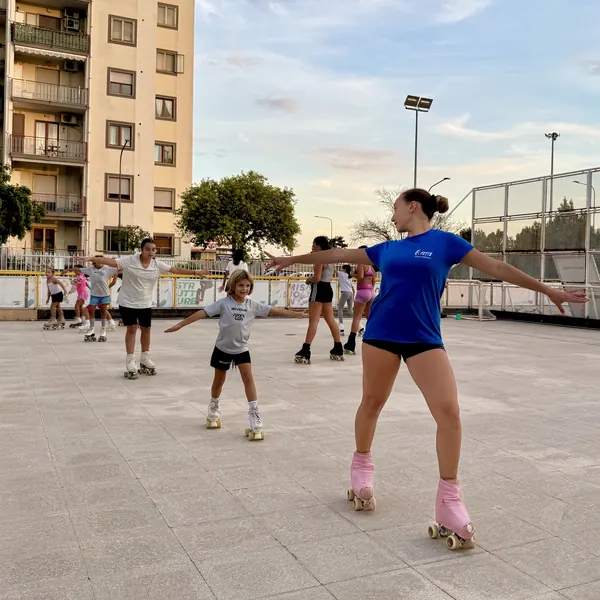 Istruttrice che mostra la posizione delle braccia agli allievi del corso di pattinaggio artistico