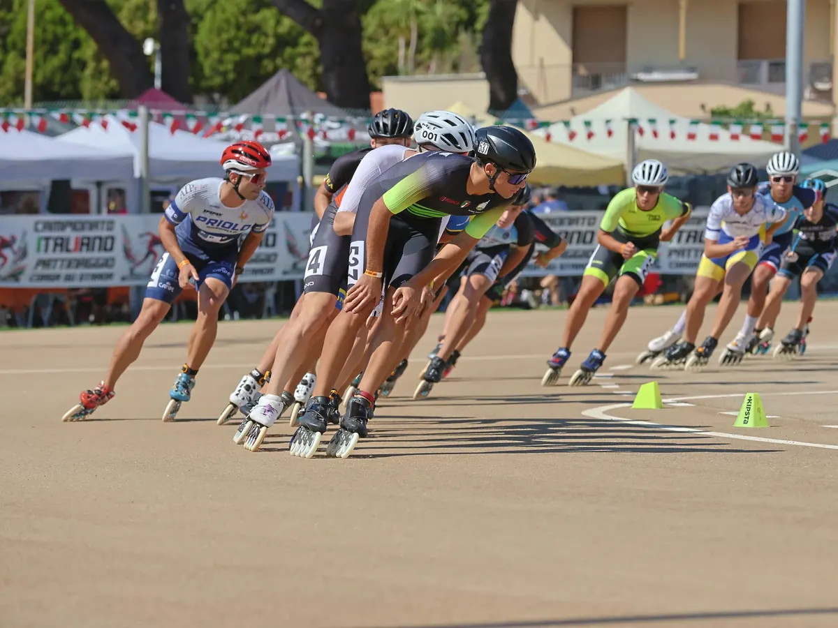 Gruppo di pattinatori piegati in curva durante una gara di pattinaggio corsa su strada ai Campionati Italiani di Vado Ligure