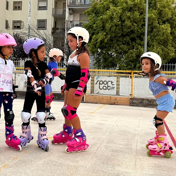 Bambine con casco, protezioni e pattini in linea al corso di pattinaggio corsa